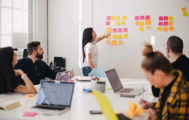 A woman instructing a workshop with her team in an office