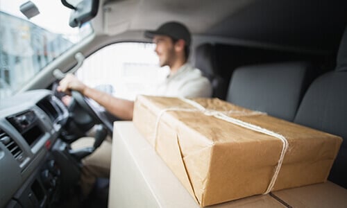 Man driving a van with two packages resting on the passenger seat